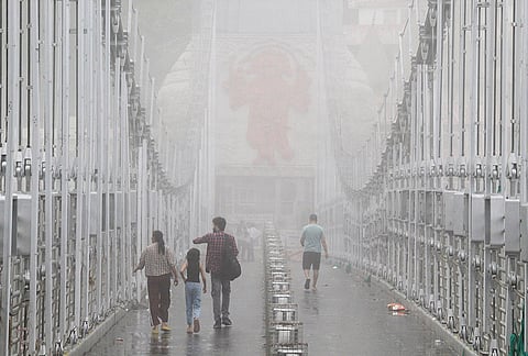 People walk across the mist-covered Lakshman Jhula following rainfall, in Rishikesh.