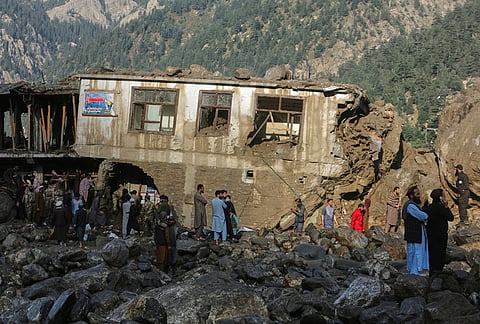 Residents and rescue workers inspect buildings damaged by heavy flooding in the eastern province of Nuristan, Afghanistan, Tuesday, July 21, 2026.