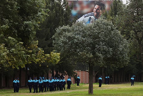 Police stand guard outside the Argentine Football Association headquarters near a banner with a photo of Argentina's Lionel Messi, before the arrival of the national team in Ezeiza, on the outskirts of Buenos Aires, Monday, July 20, 2026, following its World Cup final loss to Spain. 
