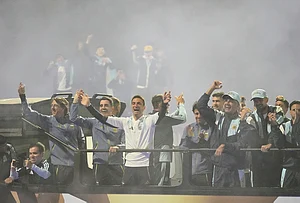 | Photo: AP/Gustavo Garello : Argentina coach Lionel Scaloni, center, surrounded by team members, waves to fans from a bus heading to the Argentine Football Association headquarters in Ezeiza, on the outskirts of Buenos Aires, Monday, July 20, 2026, after returning from the World Cup final, where they lost to Spain.