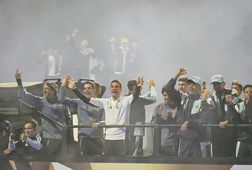 | Photo: AP/Gustavo Garello : Argentina coach Lionel Scaloni, center, surrounded by team members, waves to fans from a bus heading to the Argentine Football Association headquarters in Ezeiza, on the outskirts of Buenos Aires, Monday, July 20, 2026, after returning from the World Cup final, where they lost to Spain.