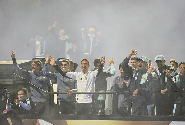 | Photo: AP/Gustavo Garello : Argentina coach Lionel Scaloni, center, surrounded by team members, waves to fans from a bus heading to the Argentine Football Association headquarters in Ezeiza, on the outskirts of Buenos Aires, Monday, July 20, 2026, after returning from the World Cup final, where they lost to Spain.