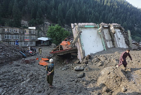 Residents and rescue workers inspect buildings damaged by heavy flooding in the eastern province of Nuristan, Afghanistan, Tuesday, July 21, 2026.