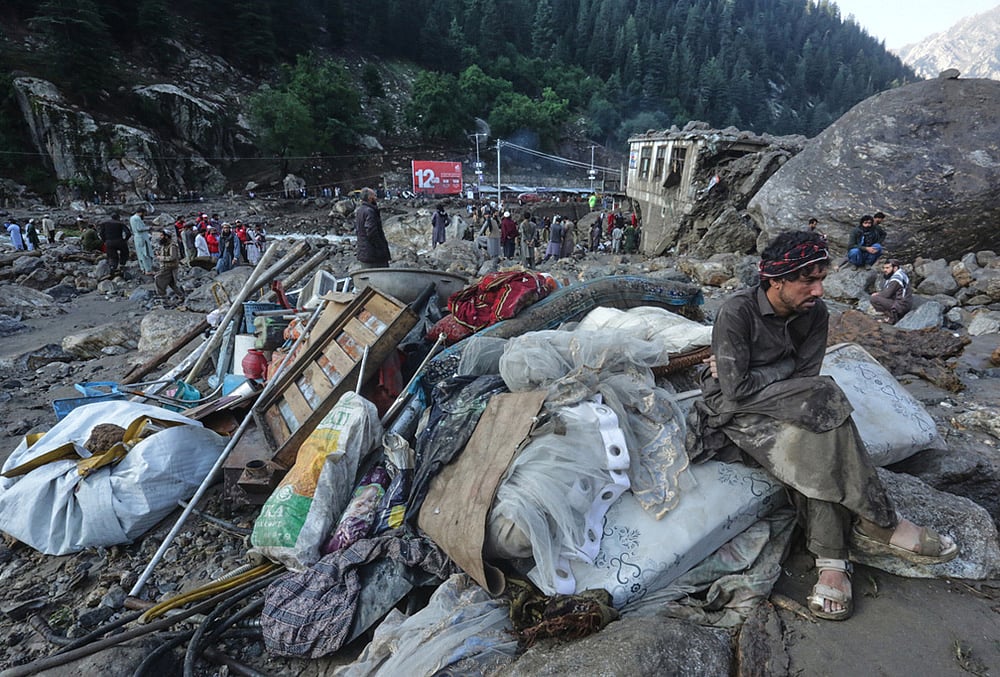 A man sits beside salvaged belongings following heavy flooding in the eastern province of Nuristan, Afghanistan, Tuesday, July 21, 2026. 