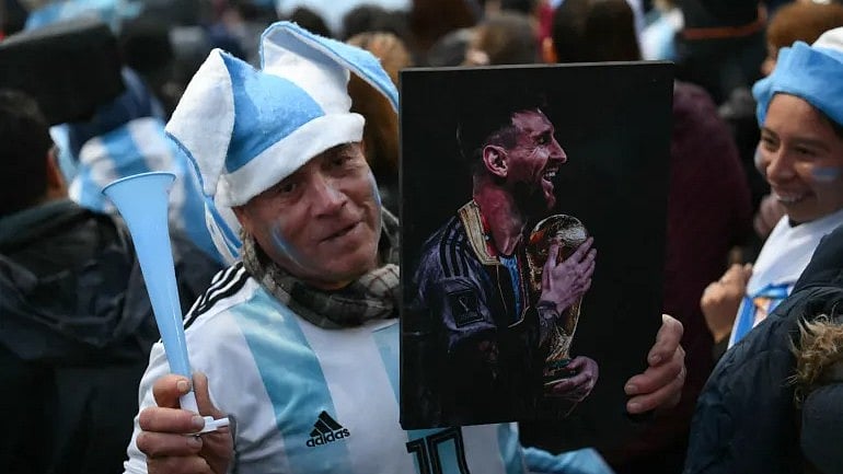 A fan holds a portrait of Lionel Messi near the Argentinian Football Association training camp in Ezeiza, Buenos Aires Province, on July 20, 2026, while waiting for the arrival of Argentina's team from the United States - AP