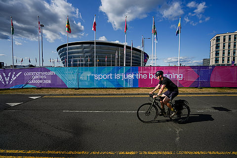 A cyclist passes participating nations' flags ahead of the Commonwealth Games 2026, in Glasgow, Scotland.