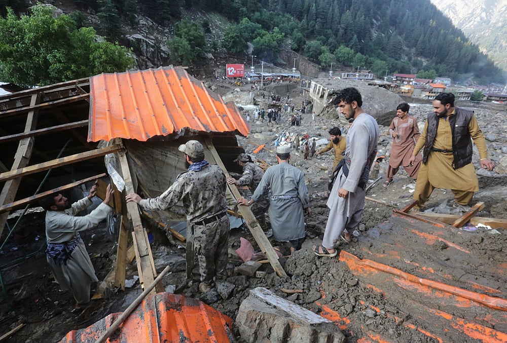 Residents and rescue workers inspect buildings damaged by heavy flooding in the eastern province of Nuristan, Afghanistan, Tuesday, July 21, 2026. 