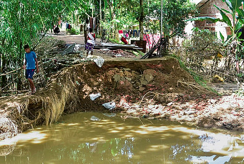 People move near the debris of a damaged house in a flood-affected area following incessant heavy rainfall, at Jhanji in Sivasagar district, Assam, Tuesday, July 21, 2026. 