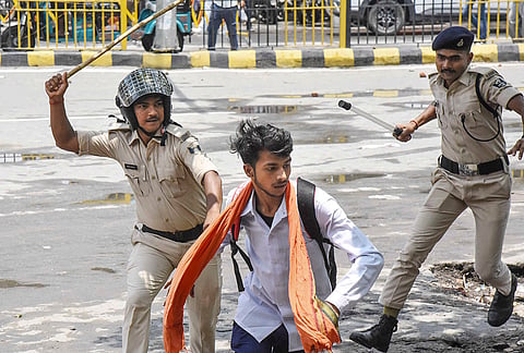 Police personnel try to evict an All India Students' Association (AISA) activist during a 'Lok Bhavan March' over alleged NEET paper leak, in Patna, Bihar.