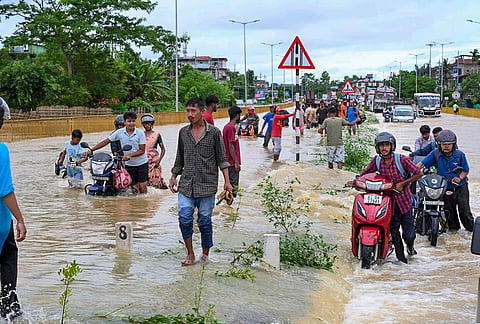 People wade through floodwaters and push two-wheelers along the submerged Jorhat-Sivasagar National Highway near Titabor, in Jorhat district, Assam, Monday, July 20, 2026. Incessant rainfall in the hills of Nagaland triggered flooding across parts of Upper Assam, affecting normal life and road connectivity. 