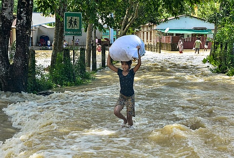 A child wades through a severely waterlogged road in a flood-affected area following incessant heavy rainfall, in Sivasagar district, Assam, Tuesday, July 21, 2026. 