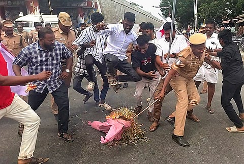 Police personnel douse a fire after Democratic Youth Federation of India (DYFI) members burn an effigy during a protest demanding the resignation of Dharmendra Pradhan over the NEET paper leak issue and the police action on students in the ‘Sansad chalo’ march, in Tiruchirappalli district, Tamil Nadu, Thursday, July 23, 2026. 