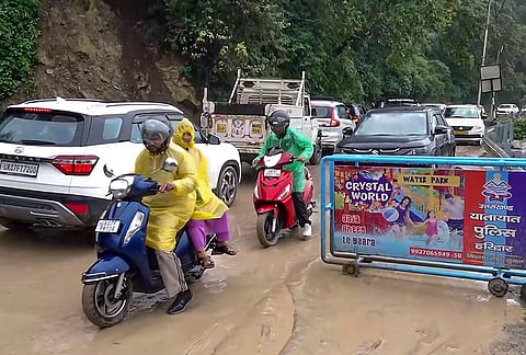 Commuters navigate a mud-covered stretch of the partially reopened Dehradun-Mussoorie road after heavy rainfall triggered landslides and damaged sections of the highway, in Dehradun.