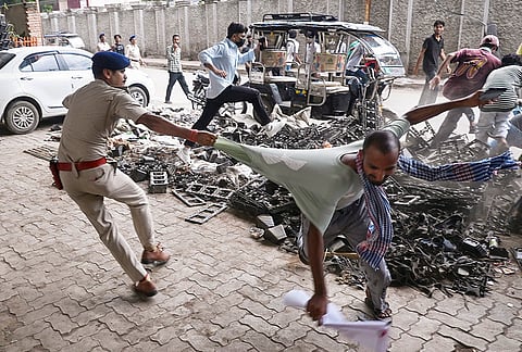 A police officer detains a protester during a demonstration demanding the resignation of Union Education Minister Dharmendra Pradhan over alleged irregularities in the NEET examination, in Patna.