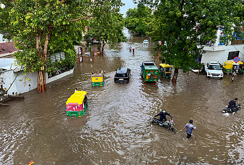 Commuters make their way through a waterlogged road following heavy rainfall, in Ahmedabad.