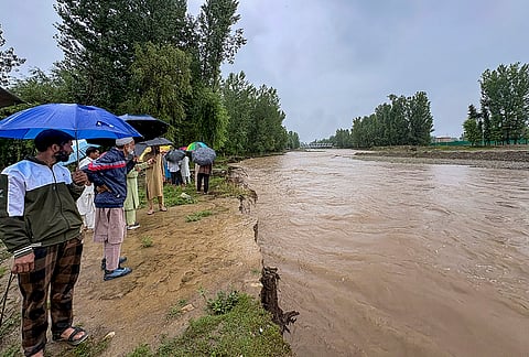 People gather after the water level of Jhelum river rises following heavy rainfall, in Anantnag, Jammu and Kashmir. The IFC Department has issued a public advisory urging residents to exercise extreme caution and refrain from venturing near rivers, streams and other water bodies. 