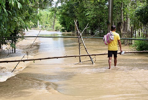 A man wades through the flood water in Teok village in upper Assam.