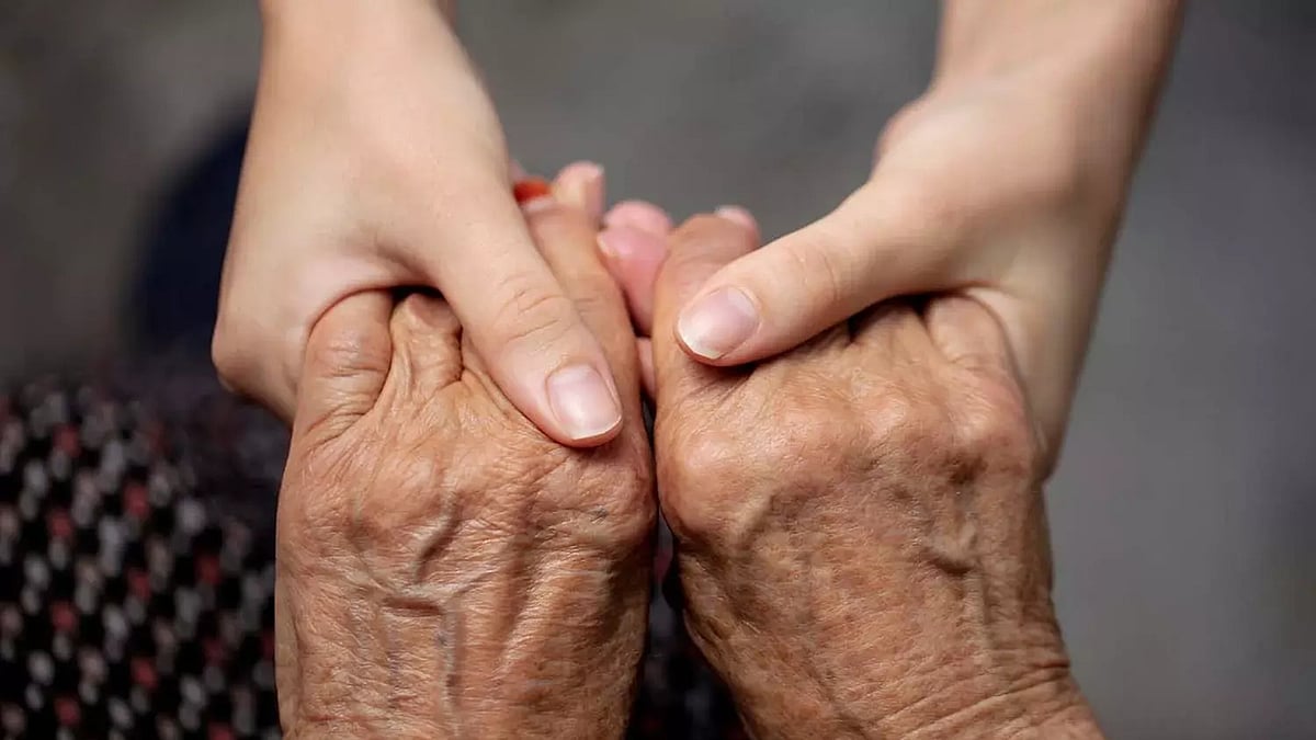A young person holding hands of an elder person