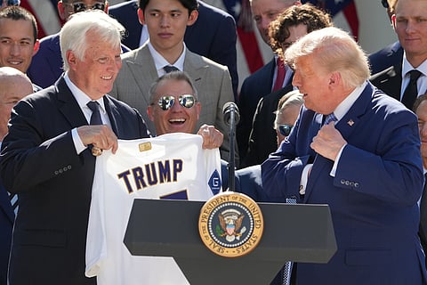 President Donald Trump puts a championship ring into his pocket as owner Mark Walter presents him with a jersey during an event to honor the 2025 World Series champions Los Angeles Dodgers in the Rose Garden of the White House in Washington.