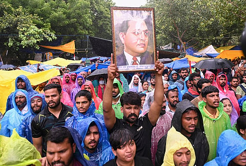 A protester holds up a portrait of Bhimrao Ramji Ambedkar, the chief architect of the Indian Constitution, during a demonstration demanding educational reforms as part of the Cockroach Janta Party's ongoing protest movement in New Delhi.