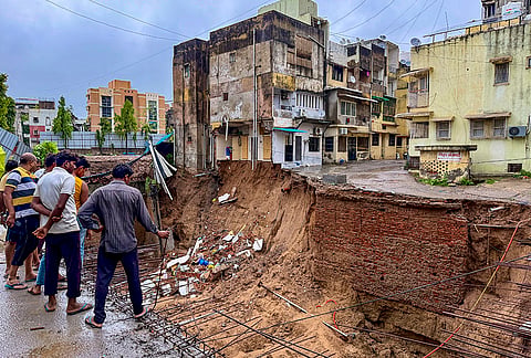 People gather near a construction site where a portion of the ground caved in following heavy rainfall, in Ahmedabad, Gujarat, Friday, July 24, 2026. 
