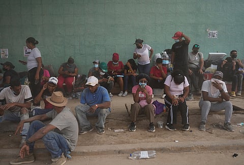 Relatives sit on a sidewalk as they wait for workers remove rubble from collapse buildings by the earthquakes, looking to find their loved ones in La Guaira, Venezuela, Thursday, July 23, 2026. 