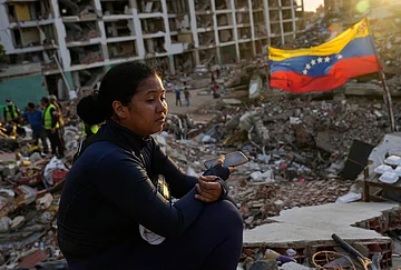 | Photo: AP/Ariana Cubillos : Estefany Landaez sits amid the rubble of a building, waiting to find her two children after the earthquakes in La Guaira, Venezuela, Sunday, July 12, 2026.