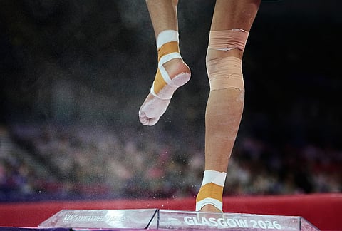 An athlete dips his feet into a chalk box before competing in the floor exercise during the men's team final and individual qualification in artistic gymnastics at the Commonwealth Games in Glasgow, Scotland, Friday, July 24, 2026.
