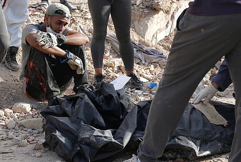 Leonel Gutiérrez sits next to the remains of his son, Dylan Gutiérrez, and the boy's mother, whom he and other volunteers recovered from the rubble of their home three weeks after it collapsed during the earthquakes that struck La Guaira, Venezuela, Friday, July 17, 2026. 