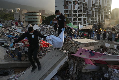 Members of Venezuela's Scientific, Penal, and Criminalistic Investigation Corps recover the body of one of Yolimar Torres's two daughters, whom the family found themselves in the rubble of a building collapsed by the twin earthquakes, in La Guaira, Venezuela, Wednesday, July 15, 2026. 