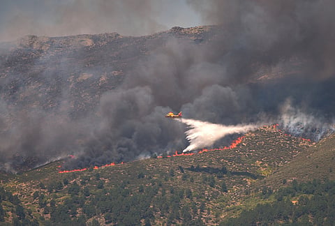 A seaplane drops water onto the fire as a wildfire advances near La Adrada, Ávila province, Spain.