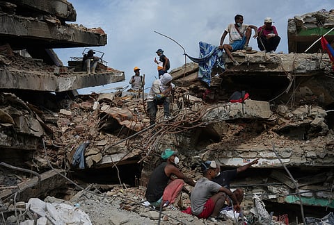 People stand on a collapsed building by the earthquakes in La Guaira, Venezuela, Thursday, July 23, 2026. 