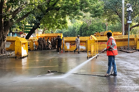 A NDMC worker washes the road during a cleanliness drive at the protest site of Jantar Mantar, in New Delhi. The Cockroach Janata Party (CJP) on Saturday called off its 36-day agitation after Education Minister Dharmendra Pradhan resigned and the government accepted its other demands.