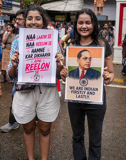 People hold posters as they take part in a rally held by Shiv Sena (UBT) chief Uddhav Thackeray, unseen, and MNS chief Raj Thackeray, unseen, to celebrate the resignation of Union Education Minister Dharmendra Pradhan, in Mumbai, Sunday, July 26, 2026. Pradhan resigned on Saturday, following which the Cockroach Janta Party called off its 36-day agitation that galvanised lakhs of people over irregularities in exams and the NEET paper leak. 