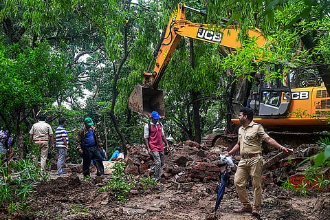 Police personnel, administration officials and people gather after the Forest Department demolishes illegal structures at Malad forest land, in Mumbai.