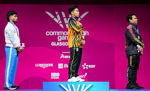 Malaysia's gold medallist Muhamad Aznil Bidin, centre, India's silver medallist Raja Muthupandi, left, and Papua New Guinea’s bronze medallist Morea Baru during the men's 65kg weightlifting final at the 23rd Commonwealth Games, in Glasgow, Scotland, Sunday, July 26, 2026. 