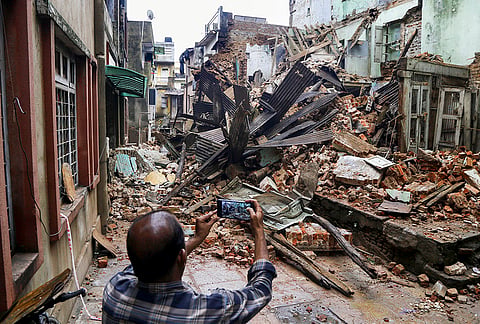 A man clicks pictures of a damaged three-storey building after it collapsed following rainfall in the Dhal Ni Pol area, in Ahmedabad, Gujarat.