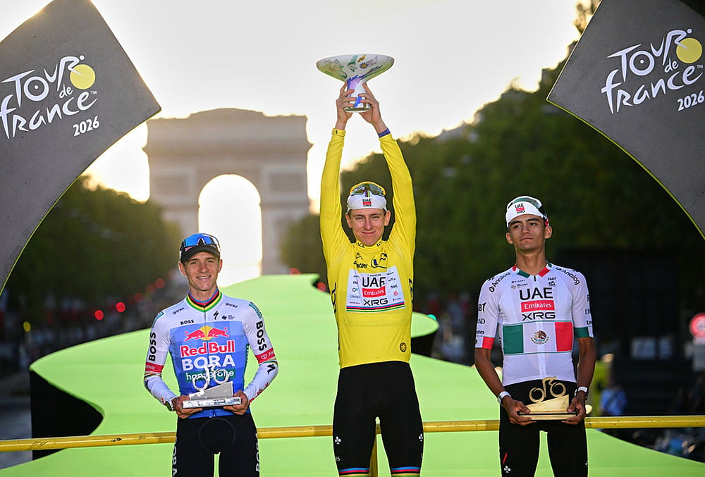 Slovenia's Tadej Pogacar, wearing the overall leader's yellow jersey, celebrates on the podium after winning the Tour de France cycling race alongside Belgium's Remco Evenepoel, second, and Mexico's Isaac Del Toro, third, in Paris, Sunday, July 26, 2026.  - | Photo: Bernard Papon/Pool Photo via AP