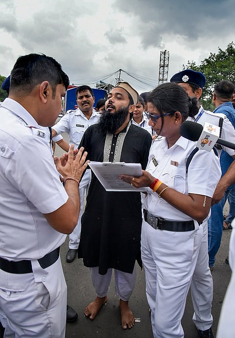 Police personnel make an accused walk barefoot after his connection in the alleged attack on media personnel during the rally of left students wing and CJP supporters on NEET paper leak issue, at Espalande area, in Kolkata, West Bengal.