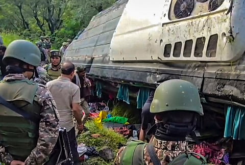 Security personnel gather near the wreckage after a bus carrying Amarnath Yatra pilgrims skids off the road and plunged into a gorge, in Ganderbal, Jammu and Kashmir.