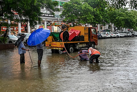 NDMC workers carry out drainage work on a waterlogged road amid rain, at Connaught Place in New Delhi, Tuesday, July 28, 2026. 