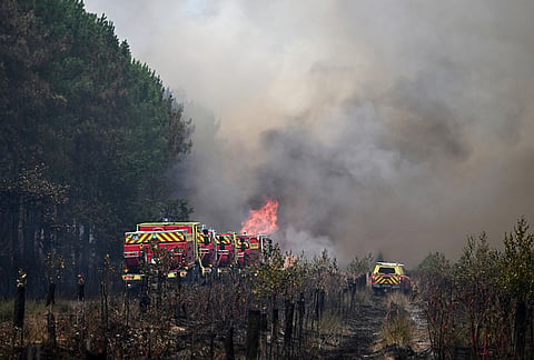 Firefighters tackle a blaze as wildfires rage near Le Las, outside Bordeaux, France, Monday, July 27, 2026. 