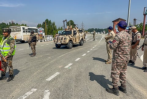 Security personnel stand guard as vehicles carrying pilgrims return after completing Amarnath Yatra from the Baltal route, in Anantnag district, Jammu and Kashmir.

