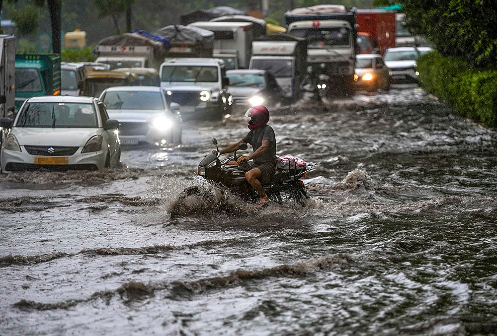 Vehicles move through a waterlogged road amid heavy rain, in the ITO area, New Delhi, Tuesday, July 28, 2026. IMD issued an orange alert in the national capital for the next few hours.  - | Photo: PTI/Salman Ali