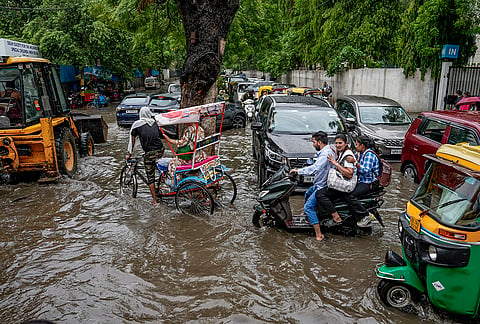 People wade through a waterlogged road following heavy rain, near Holy Family Hospital in New Delhi, Tuesday, July 28, 2026. 