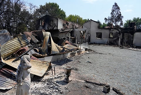 A statue stands in front of the remains of a house after wildfires raged in the village of Le Porge, on the Bay of Biscay, France, Monday, July 27, 2026. 