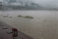 | Photo: PTI : People stand near the Janki Setu area amid rainfall, in Rishikesh, Uttarakhand.