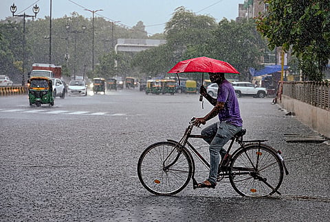 A man cycles through a waterlogged road amid heavy rain, in the Nizamuddin area, New Delhi, Tuesday, July 28, 2026. 