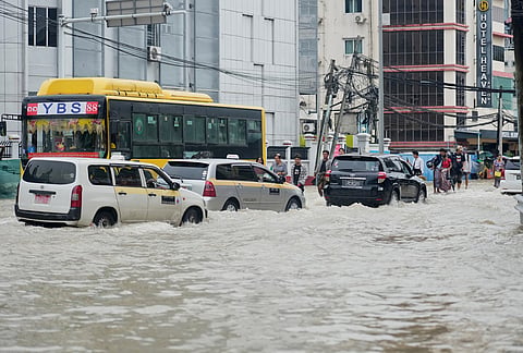 Vehicles make their ways through a road flooded due to heavy rain in Yangon, Myanmar. 