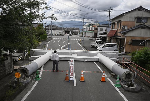 People stand by the fallen torii gate near a shrine, a day after an earthquake in Yatsushiro, Kumamoto prefecture, Wednesday, July 29, 2026.